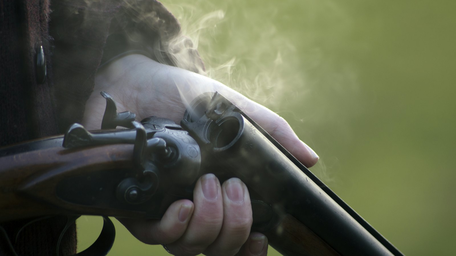 A side-by-side shotgun being closed in the field